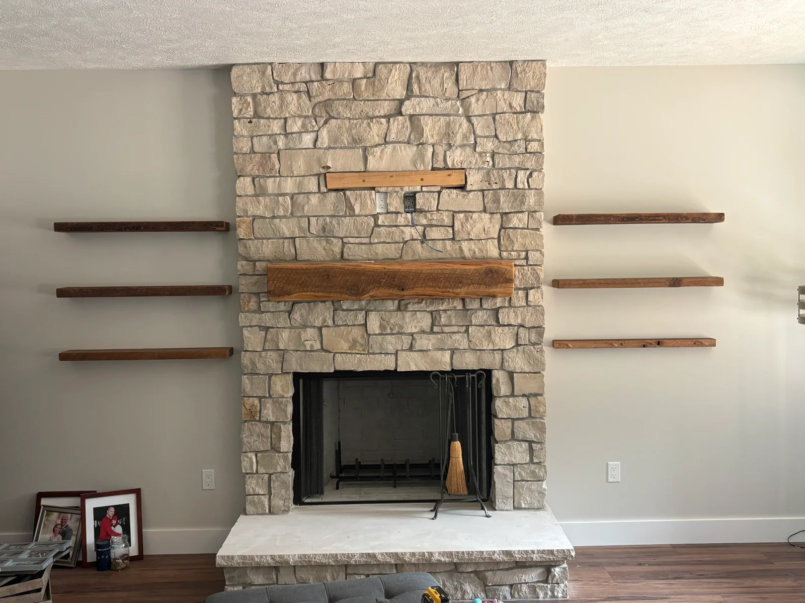 Stone fireplace with rugged natural stone veneer, live-edge wood mantel, and dark-stained wood floating shelves