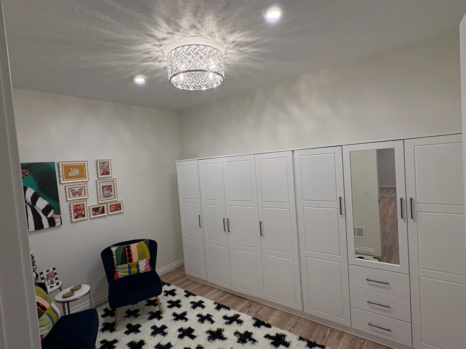 White shaker-style built-in wardrobe wall with mirror door and drawers, luxury vinyl plank floor, and shag rug